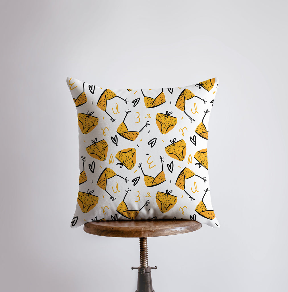 a yellow and white pillow on a wooden chair