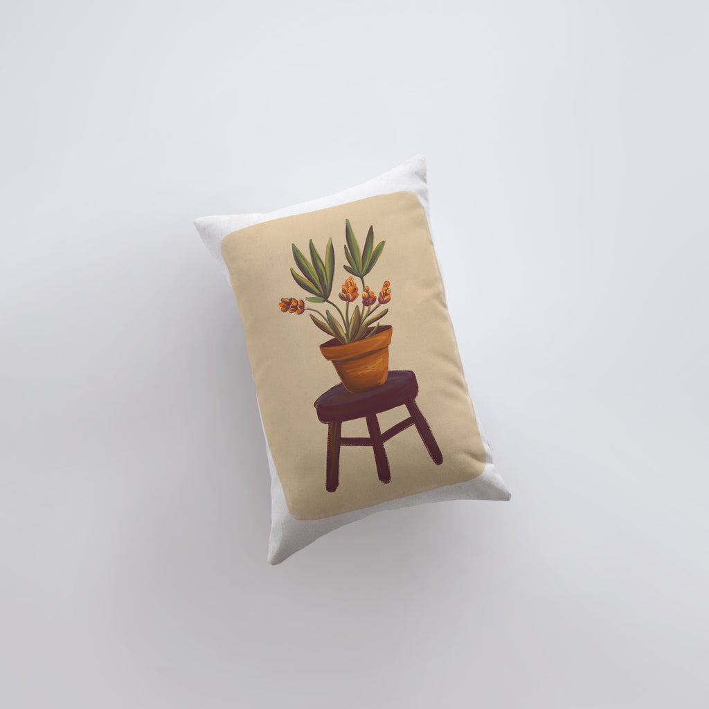 a pillow with a potted plant sitting on a stool