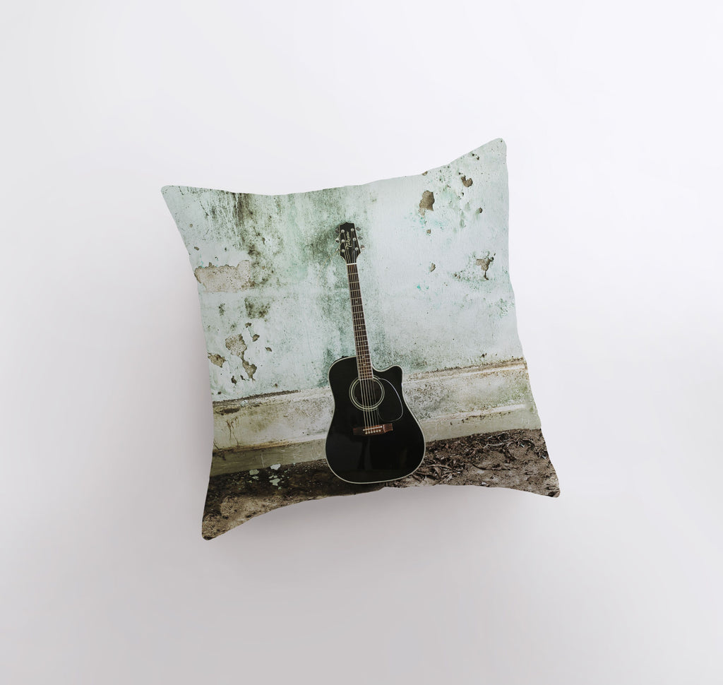 a black guitar sitting on top of a pillow