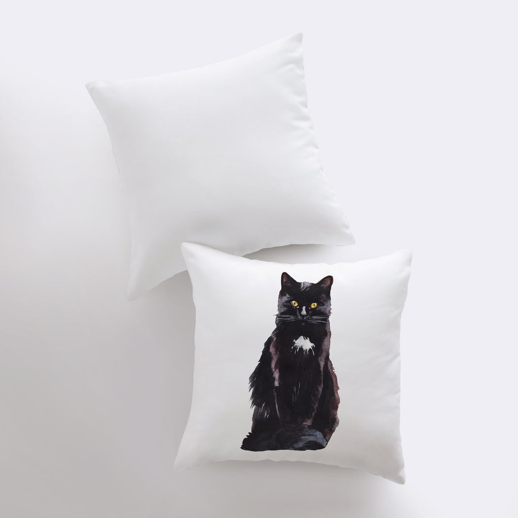 a black cat sitting on top of a white pillow