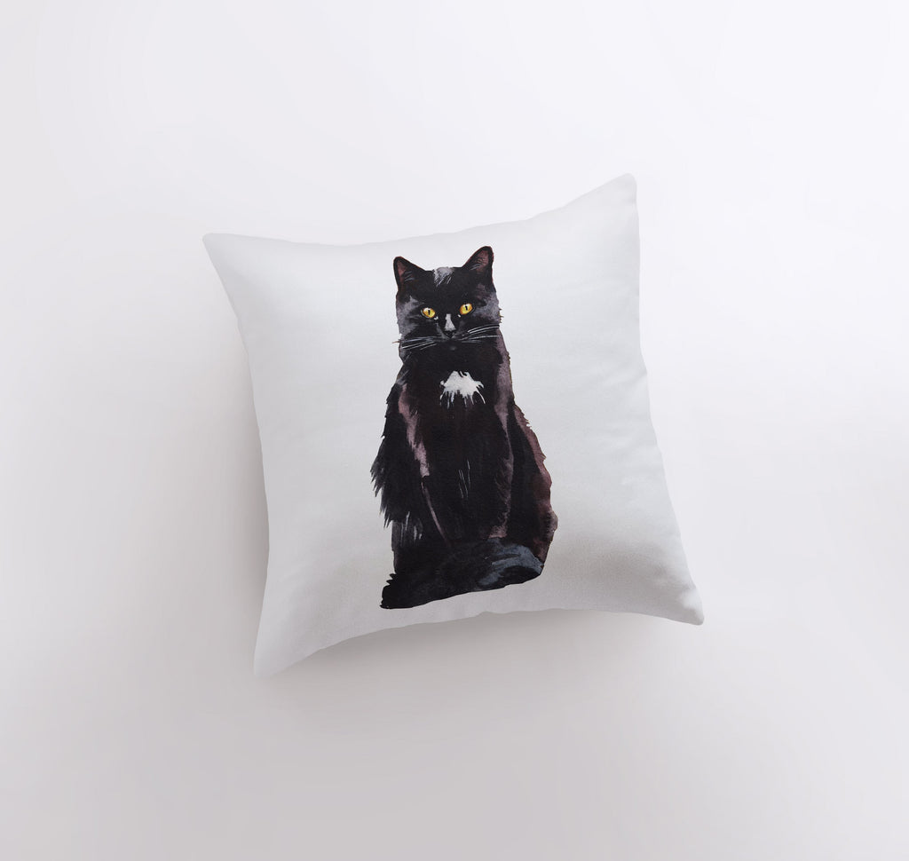 a black cat sitting on top of a white pillow