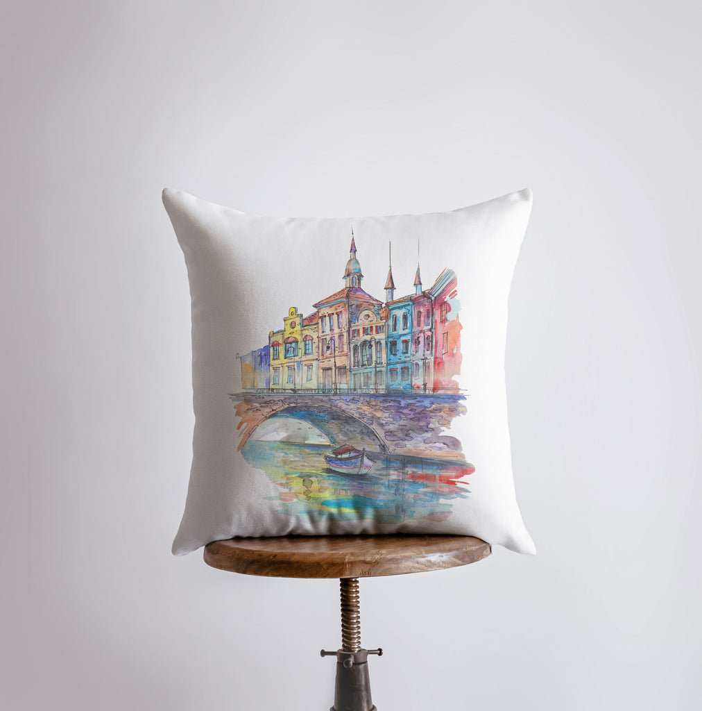 a pillow with a painting of a bridge and buildings on it