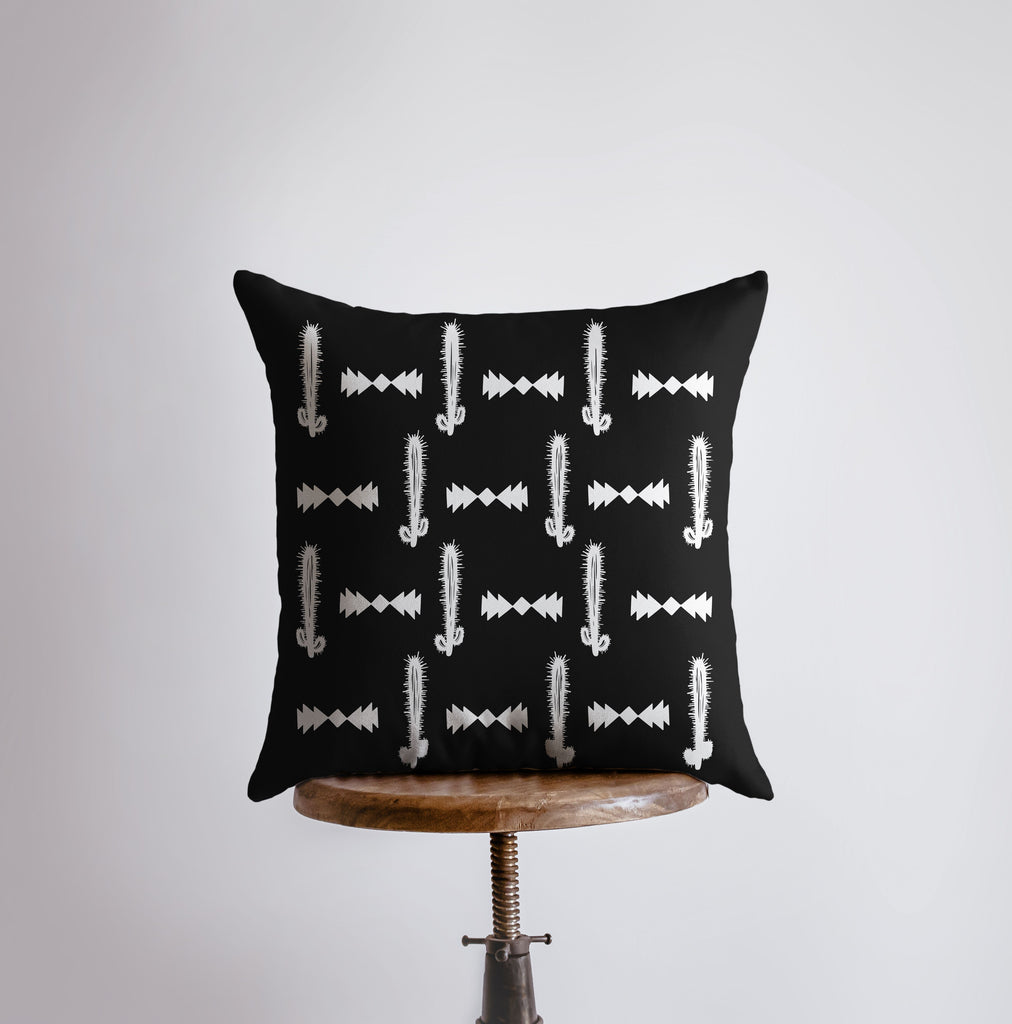 a black and white pillow sitting on top of a wooden stool