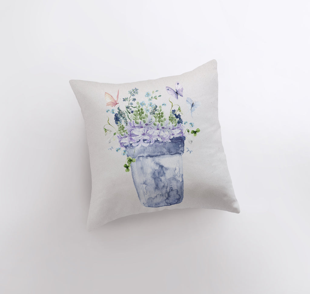 a white pillow with a blue vase filled with flowers