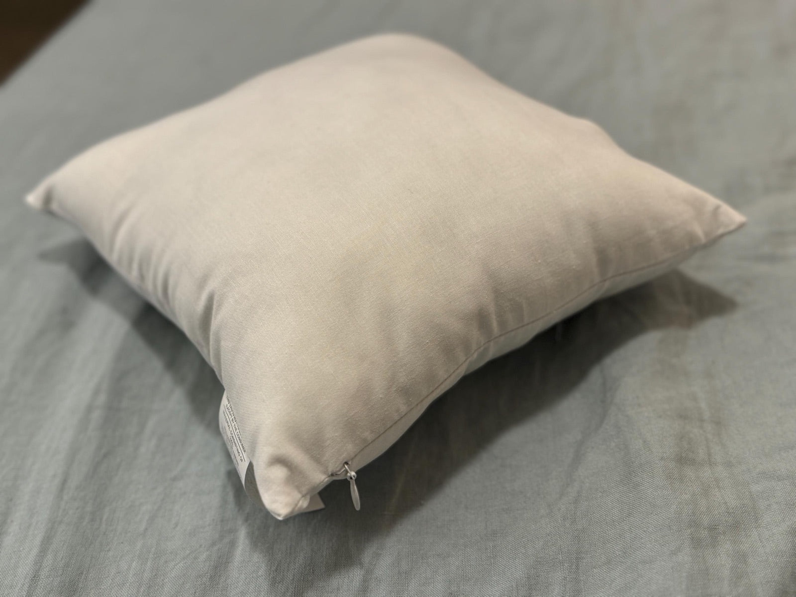Down-alternative pillow insert resting on a gray surface