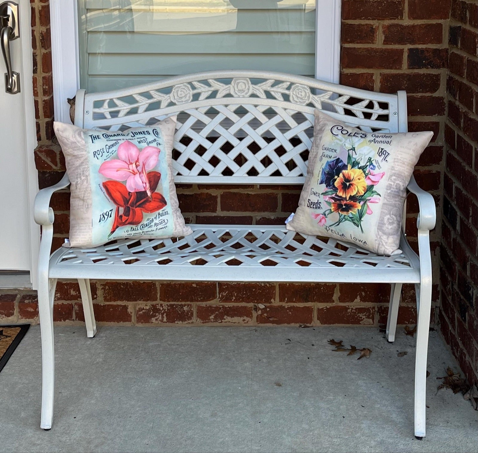 Two floral pillow covers arranged on a white porch bench