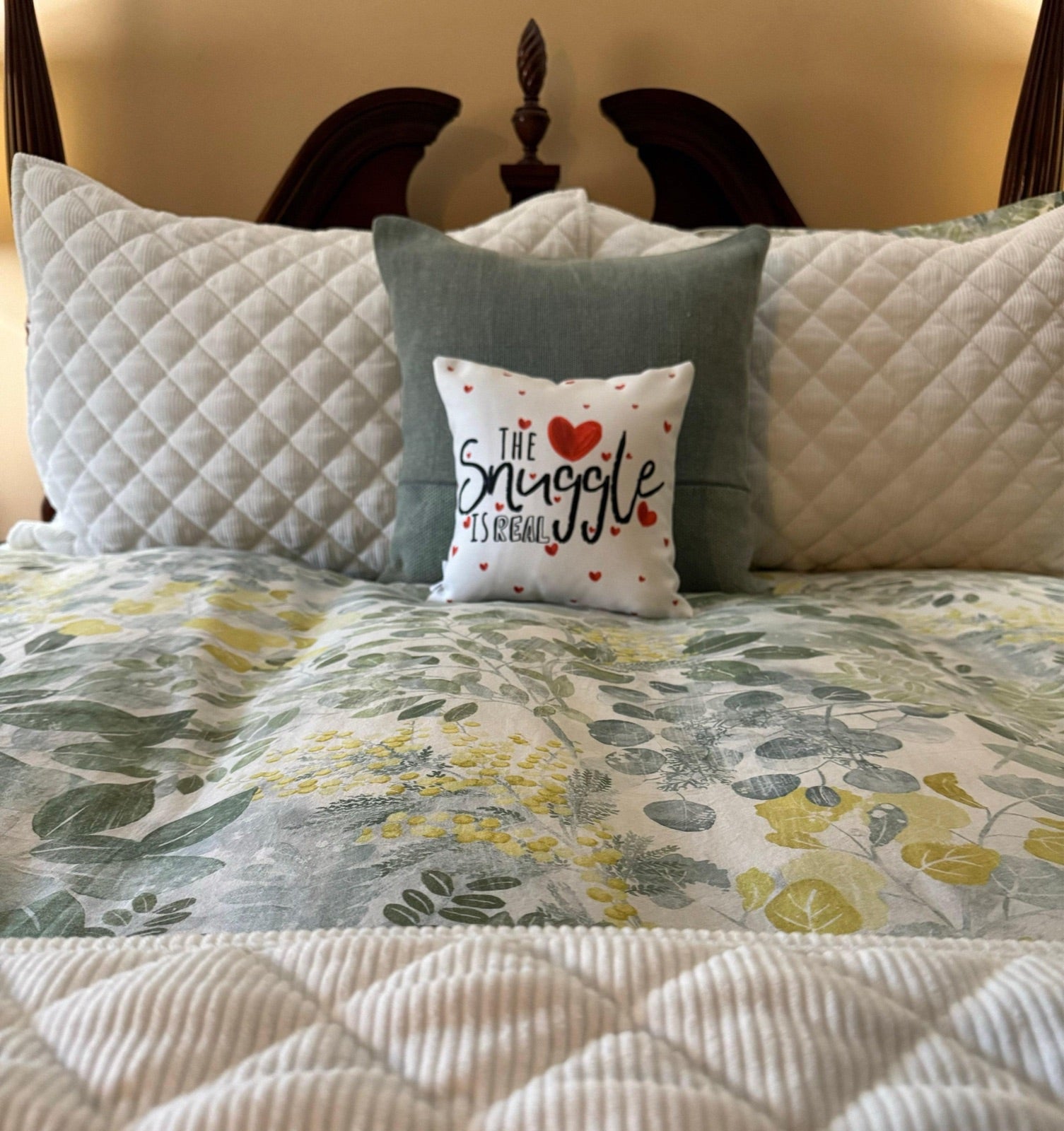 The Snuggle Is Real decorative pillow styled on a bed